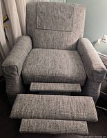 Front view of the recliner chair positioned upright with footrest extended showing texture and condition of fabric upholstery.