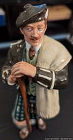 Close-up photo of Royal Doulton The Laird ceramic figure in traditional Scottish attire, holding a walking stick.