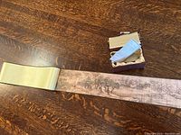 Photo showing the silk scroll unrolled partially with decorative natural scene visible and the small fabric-covered box with information sheet inside.