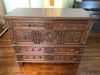 Front view showing full dresser with detailed carved wood floral panels and multiple drawers.