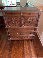 Front view of dresser showing top surface, upper drawers, and carved wooden panel doors with floral designs