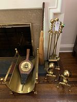 Full lot photo showing fireplace tool stand with poker, shovel, brush, broom, bellows inside brass log holder (coal scuttle). Pair of andirons beside the log holder.