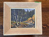 Framed oil painting of a birch forest and brook in a vintage textured light wood frame.