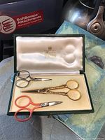 Three scissors arranged in open green case showing satin interior and foam insert