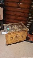 Full view of brass-covered wood box with embossed ship designs and hinged lid.