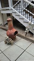 Terracotta chiminea fire pit on patio with a cherub angel garden figurine and a child figurine beside it.