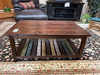Front view of wood coffee table showing rectangular top and slatted bottom shelf with visible scratches and wear.