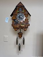 Front view of the Kaiser quartz cuckoo clock showing overall design and hanging weights.