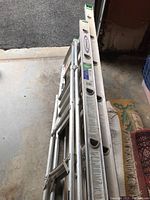 Side view of two ladders, the longer extension ladder and shorter painters ladder stacked together.