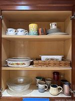 Cabinet shelf shows six tea cups with blue floral pattern, six matching saucers, four luncheon plates, one dinner plate, one coffee mug.