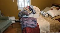 Image showing bed with folded blankets, pillows, and weighted blanket on top.