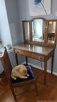 Vanity table with tri-fold mirror and chair with blue cushion, showing furniture set and upholstery detail.