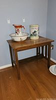 Full view of rectangular vintage wood table with items placed on top (not included in sale). Table has vertical slat sides and lower shelf.