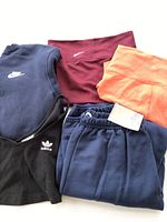 Photo showing navy blue Nike sweatshirt, maroon Nike leggings, black Adidas sports bra, orange athletic top, and blue pants.
