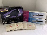 Full view of the blow dryer boxed with two curling iron boxes and four packs of nail files in front