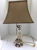 Full frontal view of hula lady lamp with fabric shade on white background.