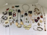 Overall display of the costume jewelry lot spread on a white surface. Shows bracelets, earrings, necklaces, and rings.