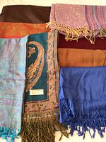 Top view of eight pashmina scarves and wraps in various colors and designs.