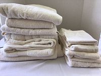Photo showing two stacks of tan towels on a surface, including bath towels on the left and hand/washcloth towels on the right.
