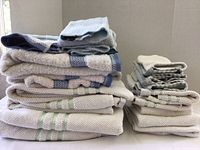 Stack of folded towels showing various styles and textures in white, blue and green trim colors.