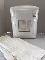 Packaged Well Dressed Home down alternative blanket in original plastic wrapping with white pillowcases beside it.