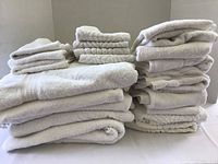 Stack of white towels showing various sizes and textures, folded and arranged on a flat surface.