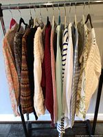 Front view of all 11 sweaters on hangers shown in profile, highlighting colors and textures