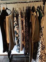 Full rack of women's medium sized brand name dress clothes on hangers showing multiple patterns and colors.