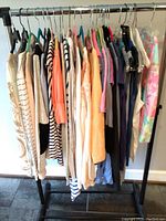 Side view of women's tops and sweaters in assorted colors and patterns on hangers