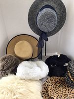 Multiple women's vintage hats including straw, fur, knit, and patterned materials arranged for display.