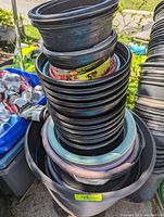 Stack of black plastic nursery pots showing colored rims and nested pots.