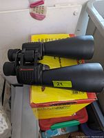 Photo showing side view of Celestron binoculars on a yellow box, highlighting black rubber body and lens barrels.
