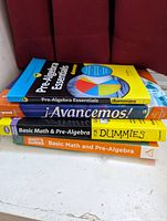 Stack of four educational books focusing on pre-algebra and Spanish language