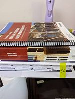 Stack of two training series workbooks: Ontario Building Code 2012 and Legal Process Qualification 2012, viewed from the side showing spiral bindings and partial cover images.