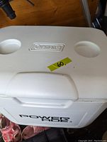 Top view of the cooler showing closed lid with two cup holders and Coleman logo embossed in the center.