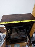 Electric fireplace showing the dark wood top surface with measuring tape indicating width.