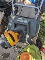 Top view of electric snow thrower showing chute and handle, with orange motor housing and green body.