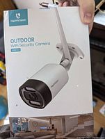 Front of the box showing the HeimVision HM311 Outdoor WiFi Security Camera image and branding.