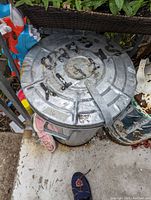 Top view of galvanized garbage can with lid and rust marks, showing scale and wear.