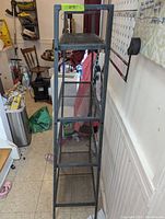 Full view of metal shelf revealing five shelves, each decreasing in depth from bottom to top, in a room interior.