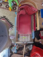 Top-down view of wooden sled showing red padded seat and wooden frame with metal runners.