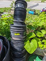 Stack of black plastic nursery pots and planters in outdoor garden setting
