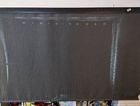 Full view of the black mesh roll up curtain spread out flat showing texture and size.