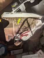 Box showing snowman yard decoration with top hat, scarf, buttons and arms, outdoors by porch.