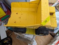Top-down view of the yellow dump bed showing wear, paint chipping, and the Tonka logo embossed on the metal bed.