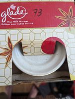 Photo of boxed Glade wax melt warmer showing partial view of white ceramic dish and product branding on box