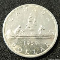 Obverse side of 1959 Canadian silver dollar coin showing a canoe with two paddlers and the date 1959.