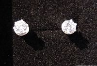 Close-up front view of one clear diamond-type stud earring on black velvet background.