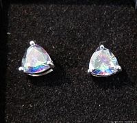 Close-up front view of two triangular iridescent mystic topaz type stud earrings showing prong settings and faceted stones.