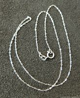 Sterling silver chain necklace laid out on a dark surface for size and detail visibility.